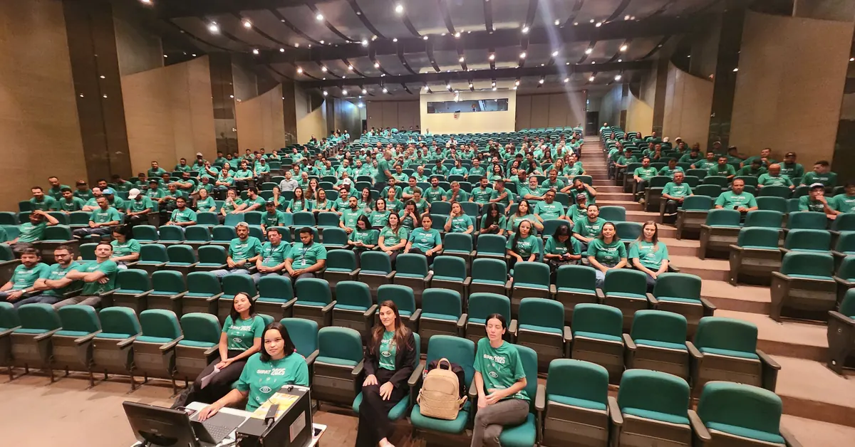 Auditório lotado de participantes com camiseta verde durante uma SIPAT.
